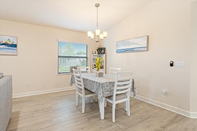 dining room with a chandelier, lofted ceiling, and light wood-type flooring