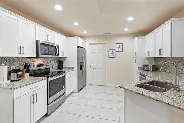 kitchen featuring appliances with stainless steel finishes, light stone counters, white cabinetry, and sink