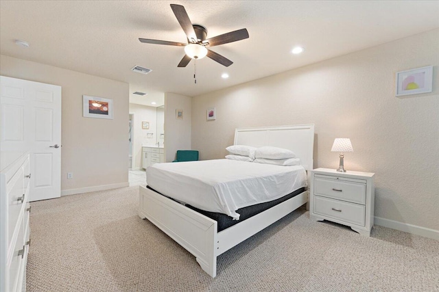 bedroom featuring ceiling fan, light carpet, and ensuite bath