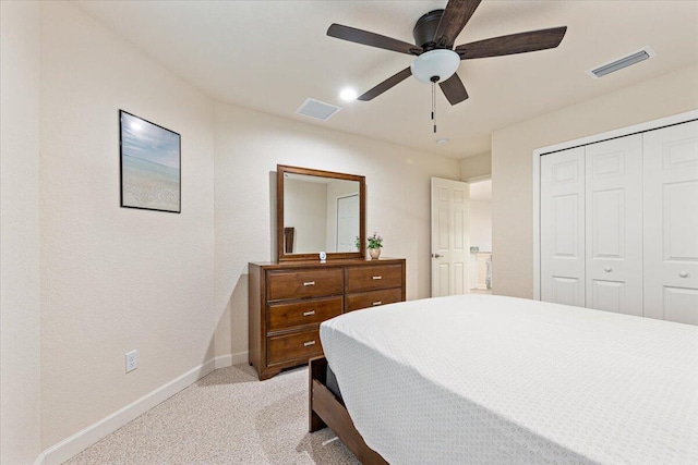 bedroom with ceiling fan, light carpet, and a closet