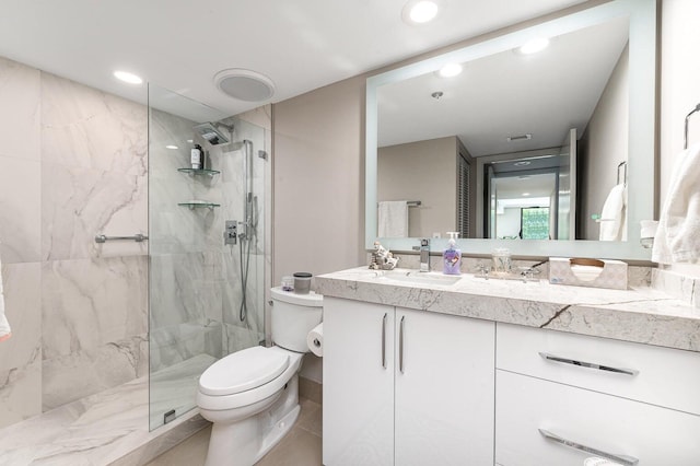 bathroom featuring a shower with shower door, vanity with extensive cabinet space, tile flooring, and toilet