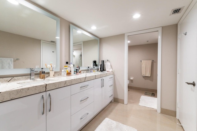 bathroom featuring oversized vanity, toilet, and double sink