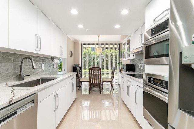 kitchen with light stone counters, stainless steel appliances, backsplash, white cabinets, and sink