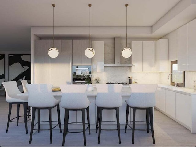 kitchen with decorative light fixtures, wall chimney exhaust hood, light hardwood / wood-style flooring, and a kitchen island