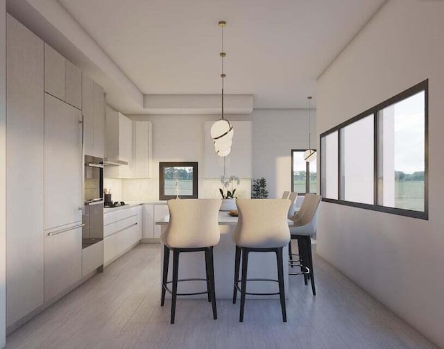 kitchen featuring decorative light fixtures, light wood-type flooring, oven, a breakfast bar, and white cabinetry