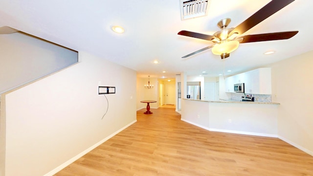 interior space with ceiling fan with notable chandelier and light hardwood / wood-style flooring