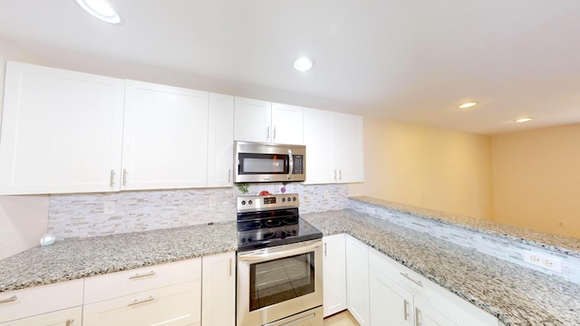 kitchen featuring white cabinetry, kitchen peninsula, stainless steel appliances, decorative backsplash, and light stone countertops