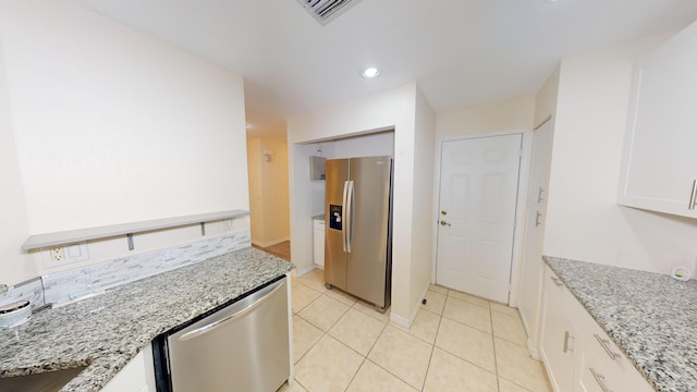 kitchen featuring light stone countertops, appliances with stainless steel finishes, light tile patterned flooring, and white cabinetry