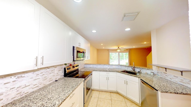 kitchen with kitchen peninsula, ceiling fan, stainless steel appliances, light stone counters, and sink