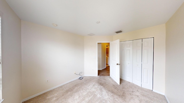 unfurnished bedroom with a closet and light colored carpet