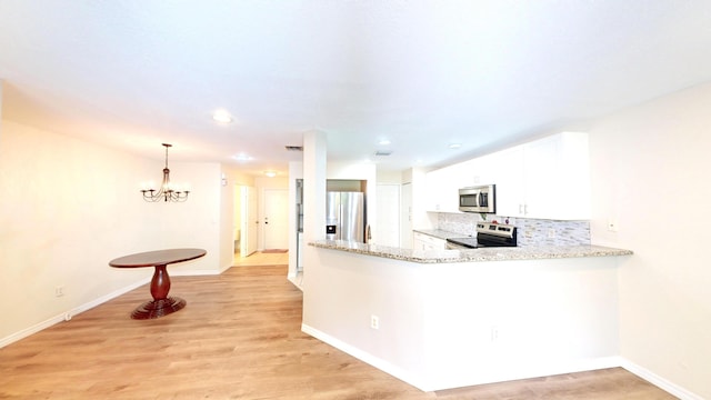 kitchen featuring an inviting chandelier, kitchen peninsula, stainless steel appliances, pendant lighting, and white cabinets