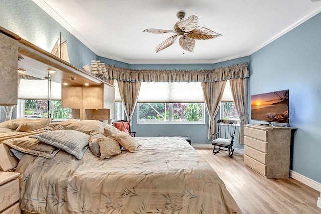 bedroom with ceiling fan, crown molding, light hardwood / wood-style floors, and multiple windows