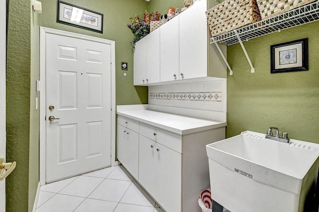 clothes washing area featuring light tile patterned floors and sink