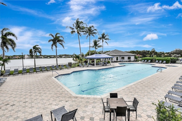 view of pool featuring a water view and a patio area