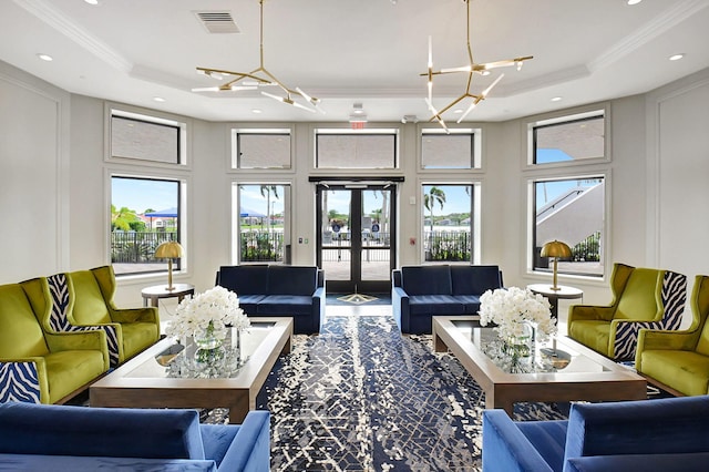 living room with an inviting chandelier, a healthy amount of sunlight, and a tray ceiling