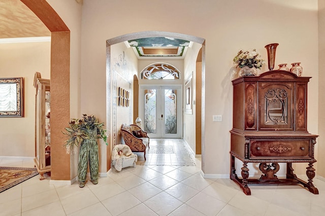 tiled foyer with ornamental molding and french doors