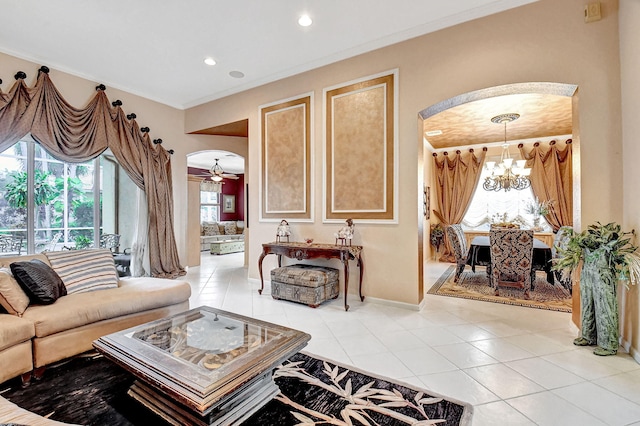 tiled living room with ornamental molding and ceiling fan with notable chandelier