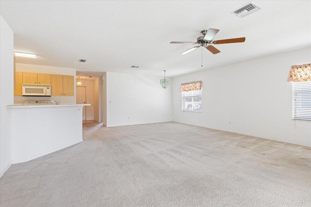 unfurnished living room featuring light colored carpet and ceiling fan