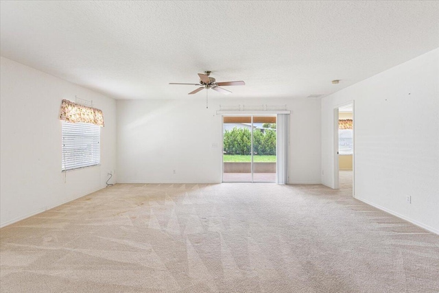 carpeted empty room featuring ceiling fan, a textured ceiling, and a healthy amount of sunlight