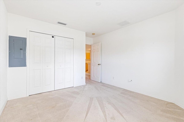 unfurnished bedroom featuring light carpet, electric panel, and a closet