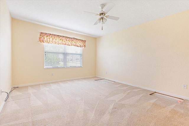 empty room with ceiling fan, light carpet, and a textured ceiling