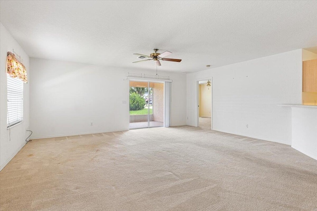 unfurnished room with ceiling fan, light colored carpet, and a textured ceiling