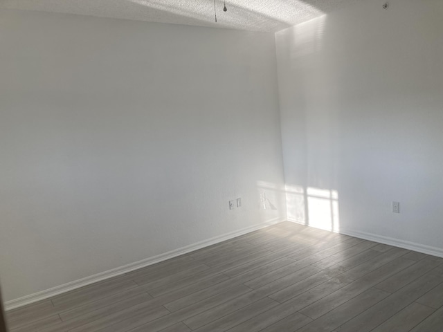 unfurnished room with a textured ceiling and hardwood / wood-style floors