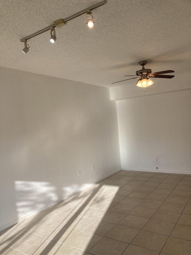 spare room featuring ceiling fan, track lighting, light tile patterned flooring, and a textured ceiling