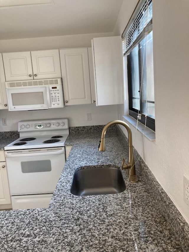 kitchen featuring white appliances, white cabinets, dark stone counters, and sink