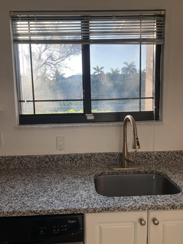 interior details featuring sink, stone counters, black dishwasher, and white cabinetry