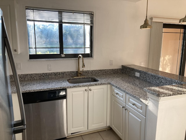 kitchen featuring appliances with stainless steel finishes, light tile patterned floors, pendant lighting, white cabinets, and sink