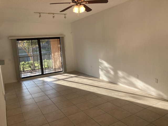 tiled empty room with a textured ceiling, rail lighting, and ceiling fan