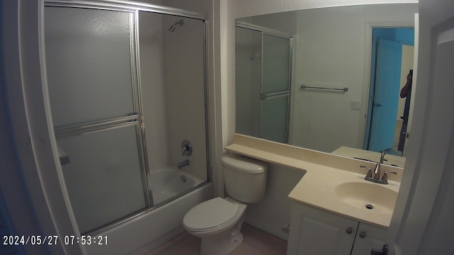 bathroom featuring vanity, toilet, and bath / shower combo with glass door