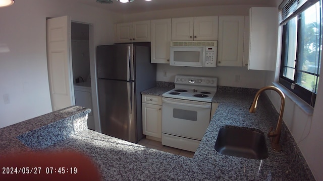 kitchen with white appliances, white cabinets, light tile patterned floors, and a sink