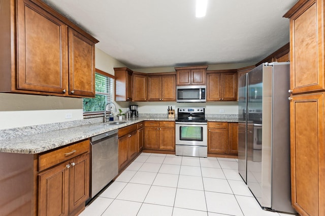 kitchen featuring light tile patterned floors, light stone countertops, sink, and appliances with stainless steel finishes