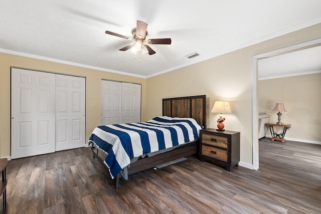 bedroom with a textured ceiling, two closets, ceiling fan, crown molding, and dark wood-type flooring