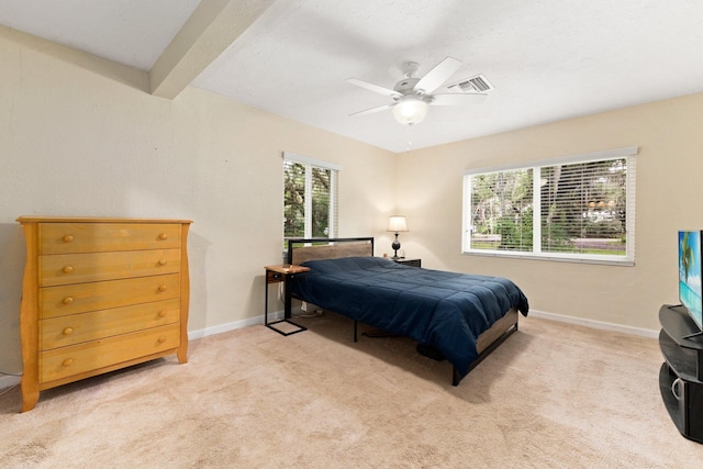 carpeted bedroom featuring beamed ceiling and ceiling fan