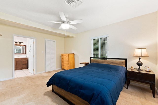 bedroom with ensuite bath, ceiling fan, a closet, and light carpet