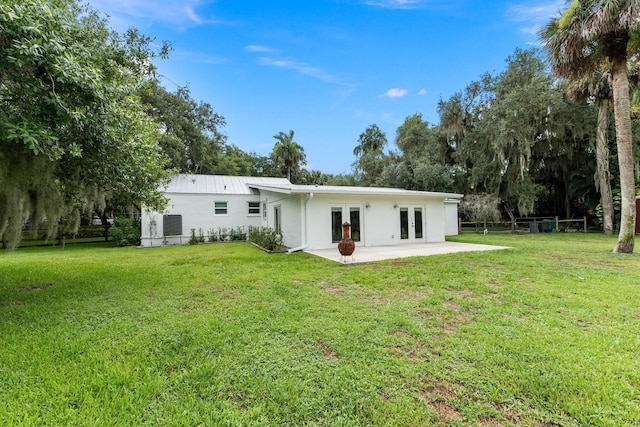 back of property with a lawn and french doors