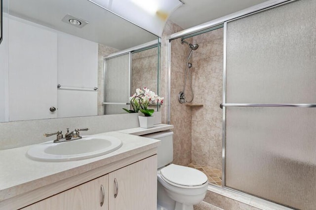 bathroom featuring a shower with door, vanity, and toilet