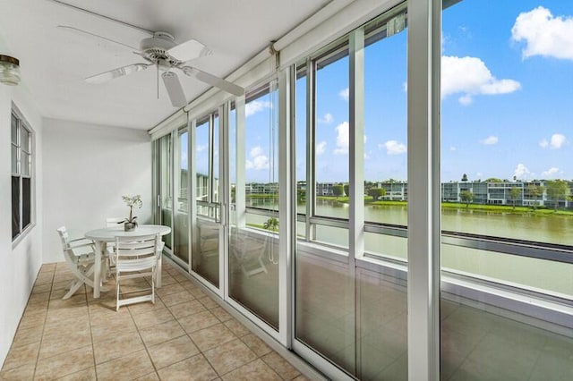 unfurnished sunroom featuring ceiling fan and a water view