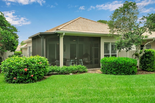 back of house with a lawn and a sunroom