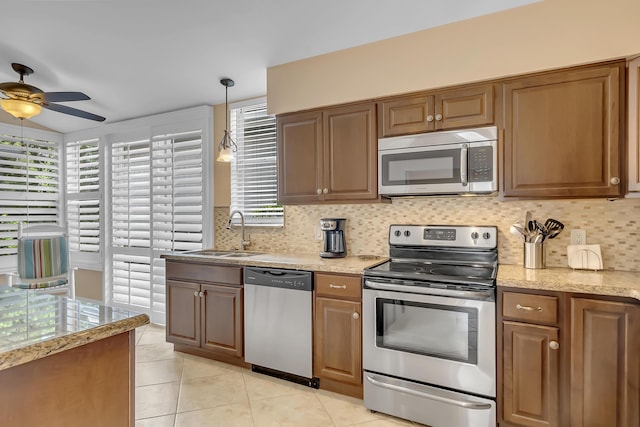 kitchen with appliances with stainless steel finishes, backsplash, ceiling fan, sink, and hanging light fixtures