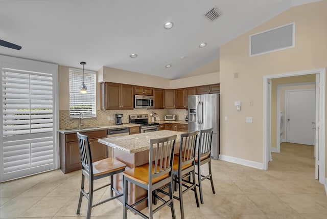 kitchen featuring vaulted ceiling, sink, decorative light fixtures, and appliances with stainless steel finishes