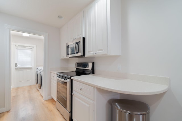 kitchen with white cabinetry, washing machine and dryer, light hardwood / wood-style flooring, and appliances with stainless steel finishes