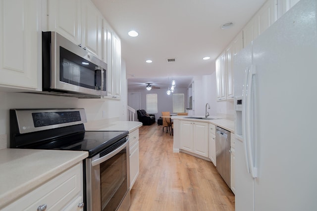 kitchen with white cabinetry, ceiling fan, sink, appliances with stainless steel finishes, and light hardwood / wood-style flooring