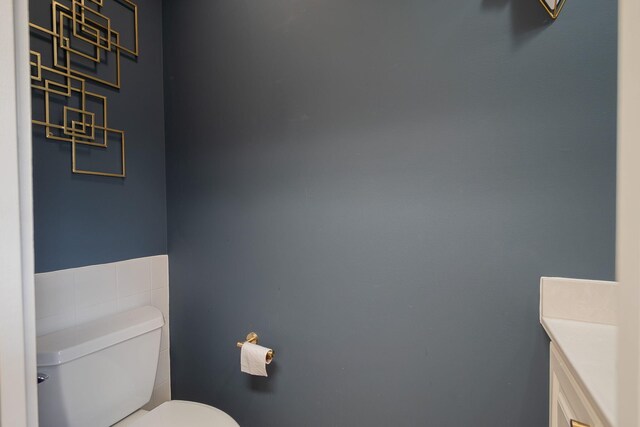 bathroom with tile walls, toilet, and vanity