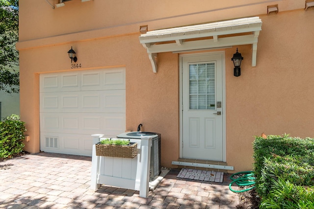 property entrance featuring cooling unit and a garage