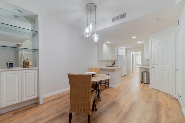 dining room with sink and light wood-type flooring