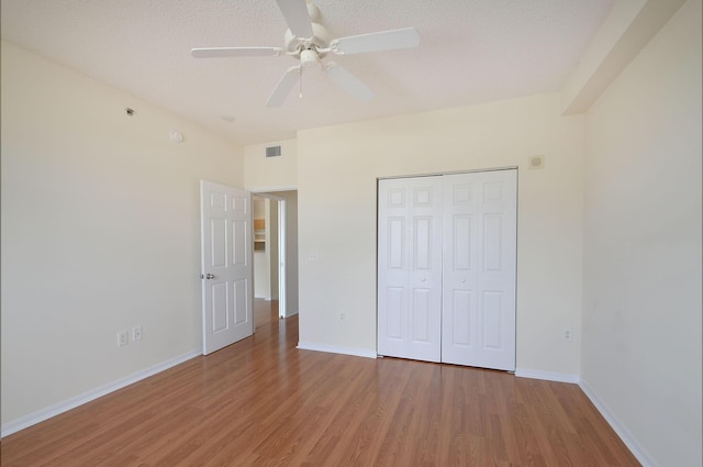 unfurnished bedroom featuring hardwood / wood-style floors, ceiling fan, a textured ceiling, and a closet